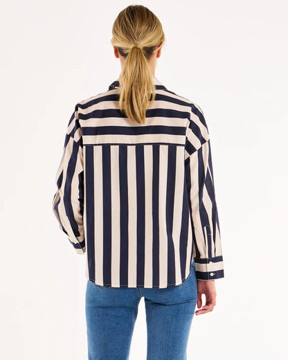 back image of a women wearing white and blue striped shirt untucked into jeans