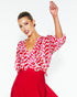 women wearing red and white wavy geometric wave pattern blouse with 3/4 length sleeves